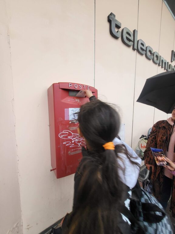 Bambina spedisce una cartolina nella cassetta delle Poste