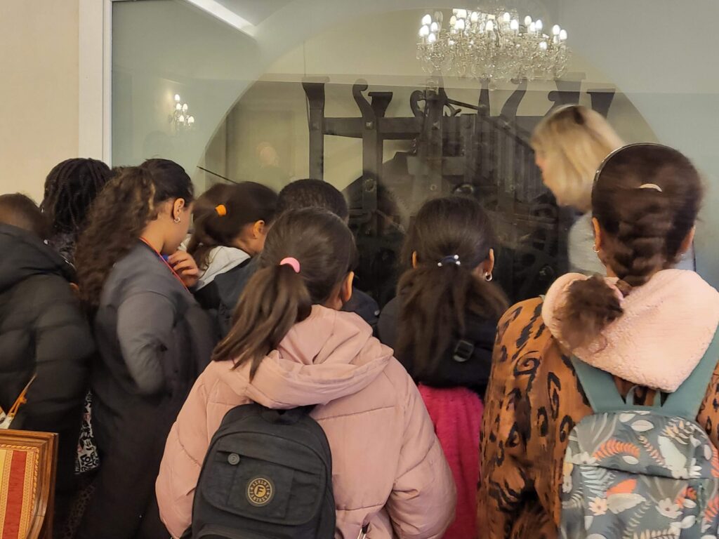 Bambini osservano il meccanismo dell'orologio in sala Ferracina